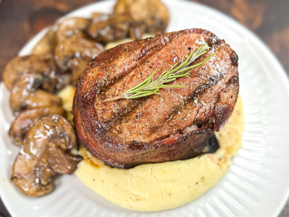 Bacon wrapped tenderloin filet mignon on mashed potatoes with mushrooms